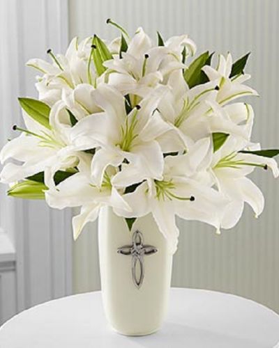 This striking display of pure white lilies will send your heartfelt expressions when words just aren't enough. Arranged in a white ceramic vase and enhanced by a cross, this arrangement is perfect for celebrations, confirmations, sympathy, weddings, or a special anniversary.This is an all-around arrangement.